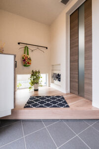 地窓からの光で明るさを確保した玄関ホールは、コートのハンガーパイプを設置しました。