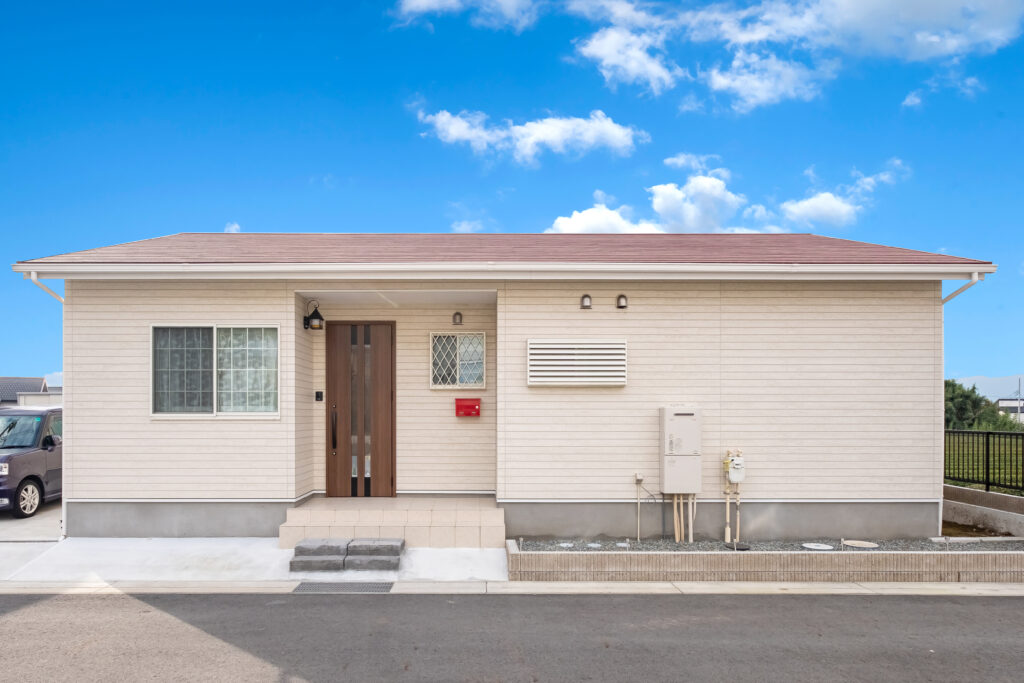 淡い外壁と赤い屋根を組み合わせたシンプルな平屋の正面外観