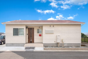 淡い外壁と赤い屋根を組み合わせたシンプルな平屋の正面外観