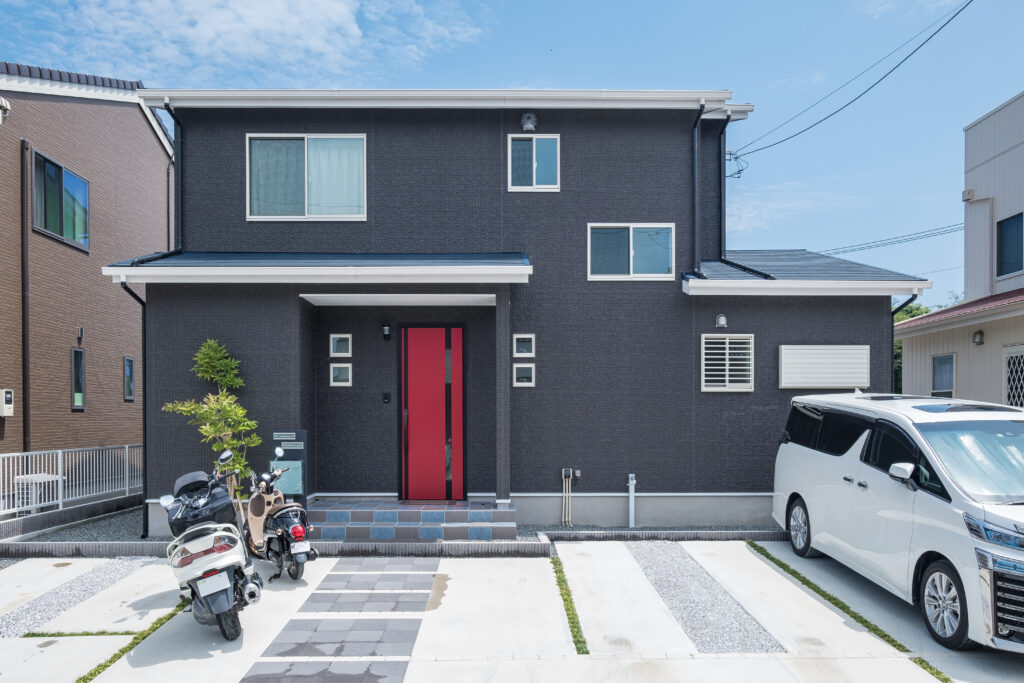 黒い外壁に赤い玄関ドアを合わせた2階建て住宅の外観