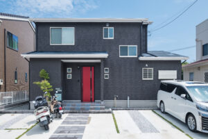 黒い外壁に赤い玄関ドアを合わせた2階建て住宅の外観