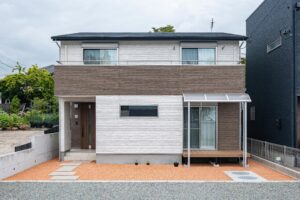 白とブラウンの外壁を組み合わせた二階建て住宅の正面外観