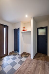 明るい床タイルの玄関とハンガーパイプを備えたシューズクローク