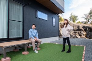 人工芝とウッドデッキを設けた庭で過ごす夫婦